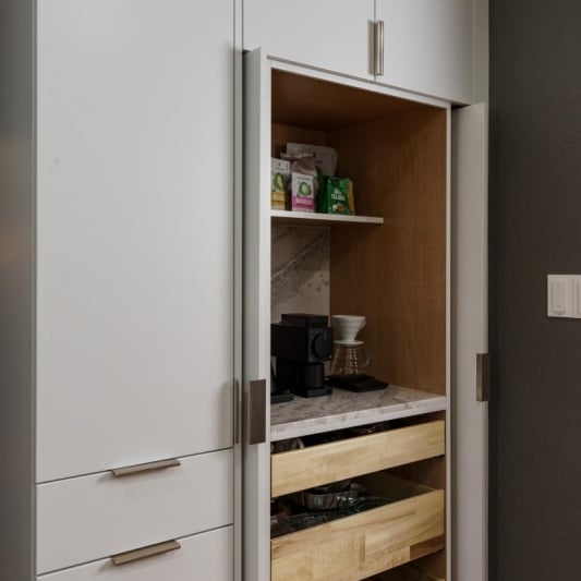 n interior view of a recently remodeled KCMO kitchen featuring built-in white cabinets with a coffee station, light wood drawers, and a dark gray accent wall.