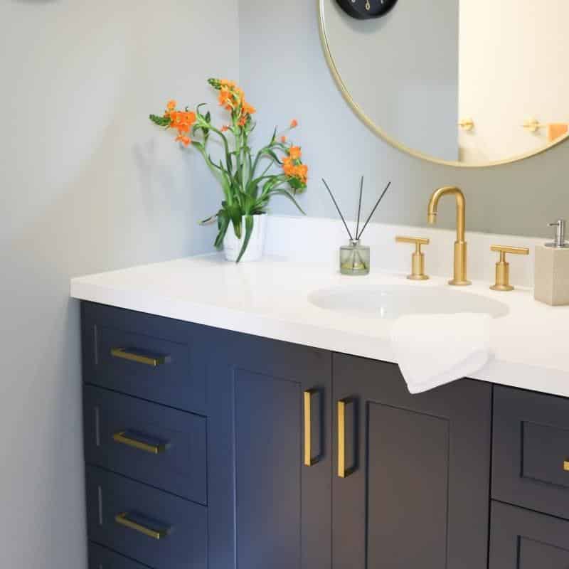 modern bathroom update with bright white shower and navy vanity and brass accents