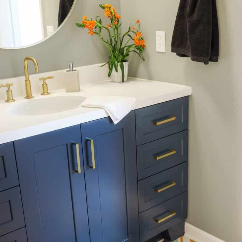 modern bathroom update with bright white shower and navy vanity and brass accents