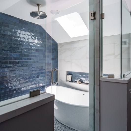 modern spa like wet room with blue subway tile accent and large white soaking tub