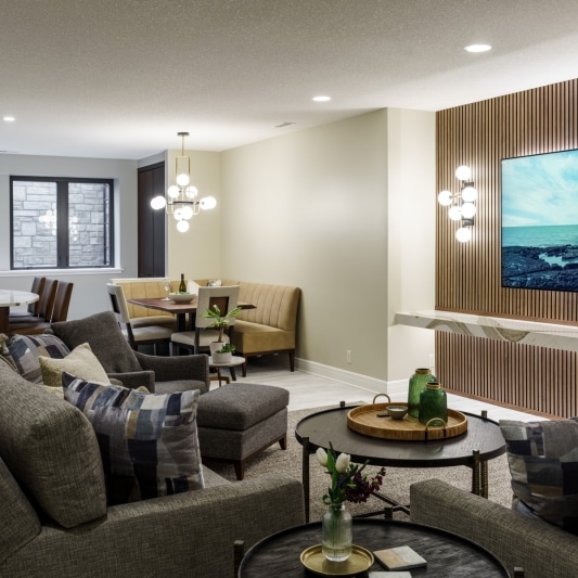 Spacious open-concept basement living area with a TV lounge, dining nook, and bar area.