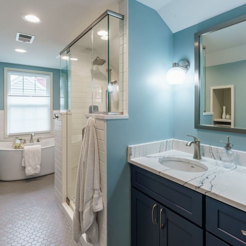 cape cod bathroom remodel with blue accents, large soaking tub, walk-in shower and blue vanity with cambria quartz counters