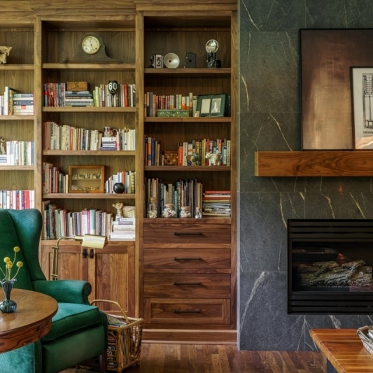 fireplace framed by warm stained wood built in shelves from floor to ceiling