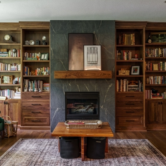 fireplace framed by warm stained wood built in shelves from floor to ceiling