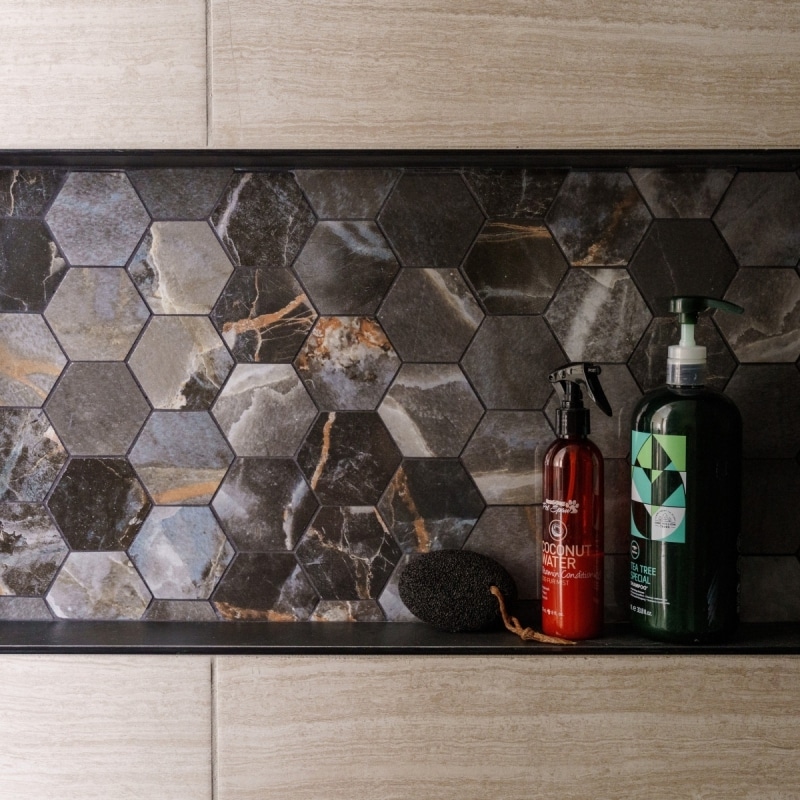 modern shower niche that features hexagon dark stone accent tile