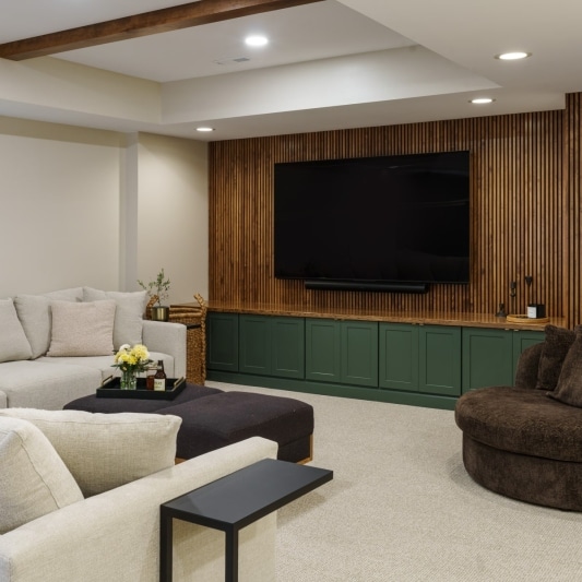 Living area with wood slated wall, beams in tray ceiling, and green built-ins
