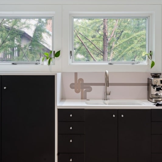 sleek contemporary kitchen remodel with black matte cabinets and white oak and full height backsplash with unique accents
