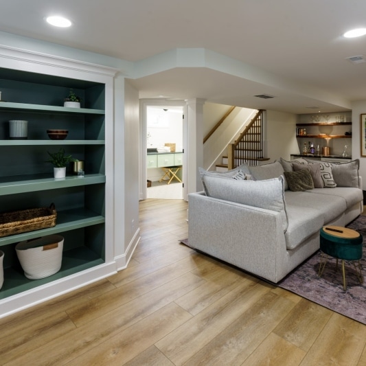 Basement with green built-in shelves, vinyl wood flooring, and white walls