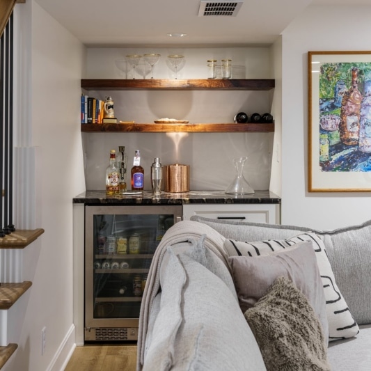 Basement steps with white oak steps, black spindles, and built-in bar with open shelves