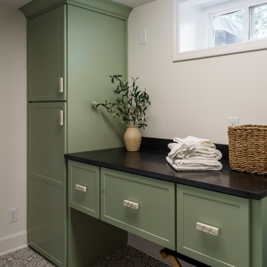 Laundry room with green cabinetry black granite tops