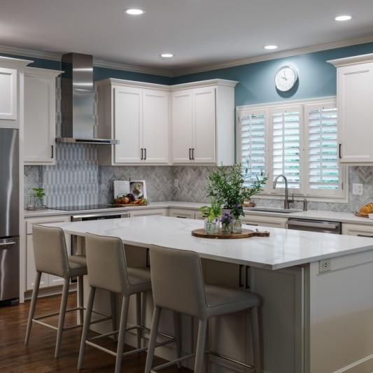 White kitchen with blue painted walls and marble mosaic backsplash