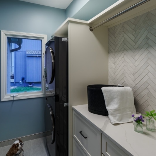 Laundry room with stacked washer and dryer and herringbone backsplash