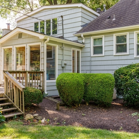 Rear view of a multi-level house with a sunroom addition