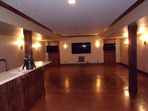Basement before move theater. Open space with stained cement floor and pillars