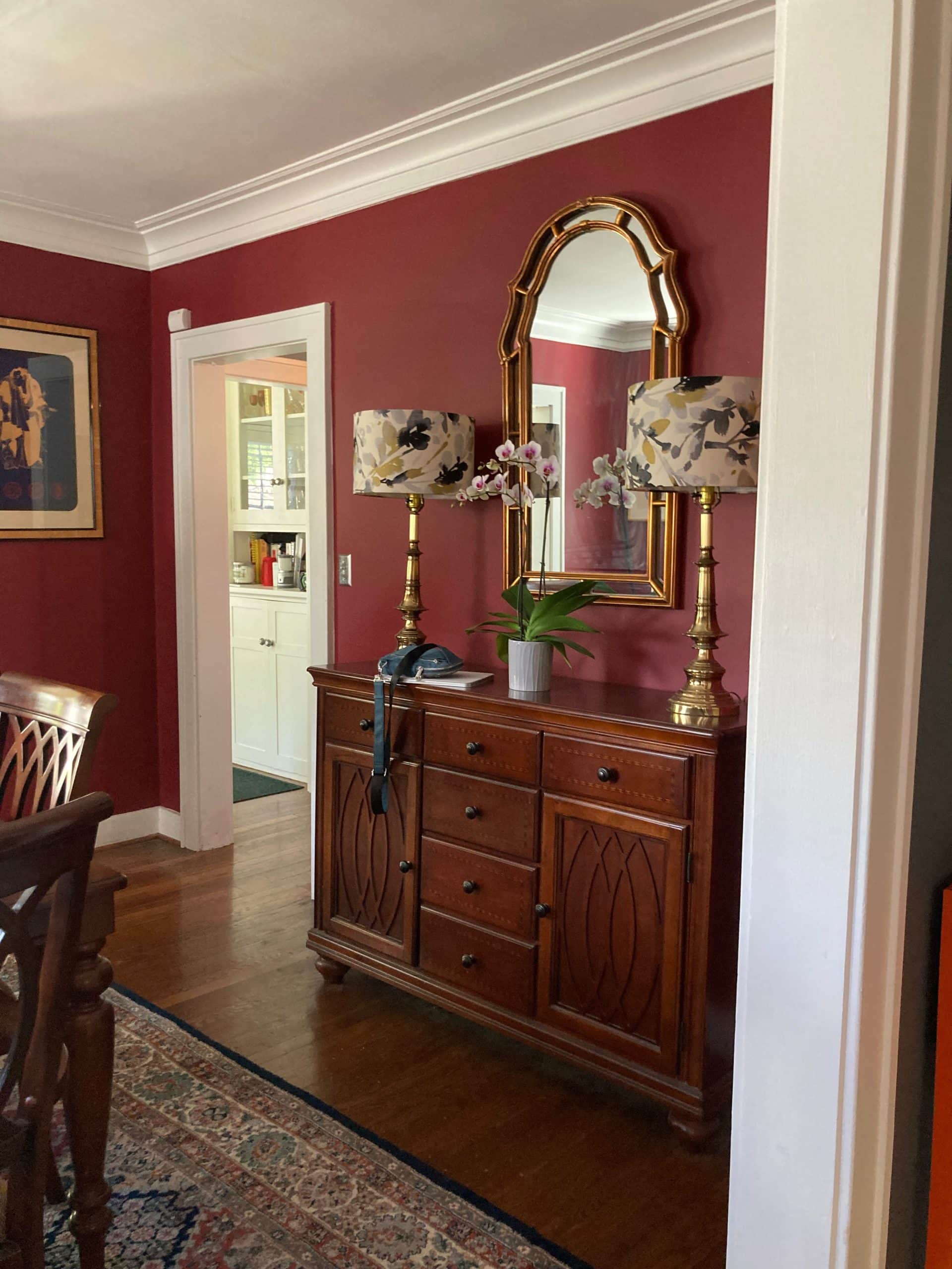 before photo of the red dining room with traditional dark cherry wood cabinet storage piece and oriental rug on floor, soon this will will be removed and open up into the kitchen space