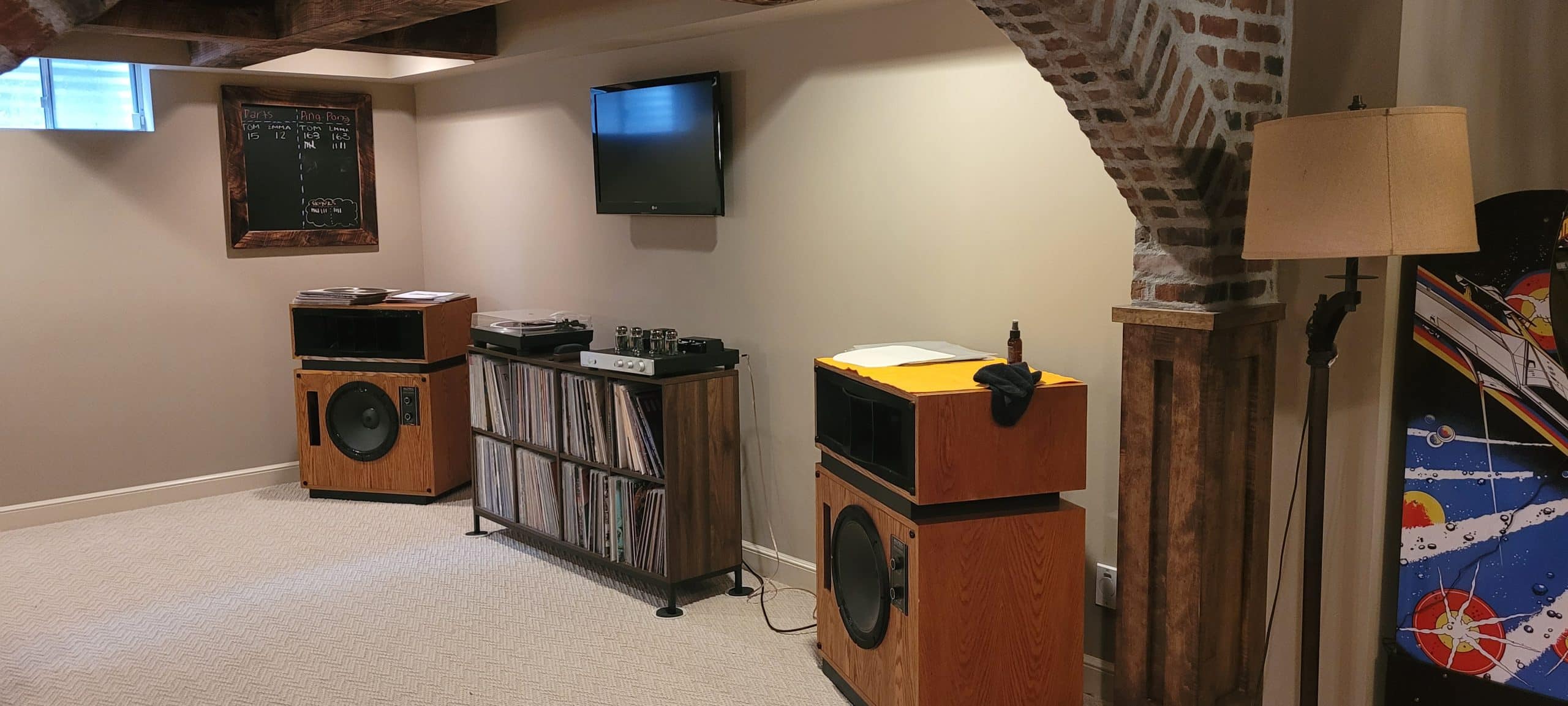 View from kitchen area of basement into the listening area with speakers. 