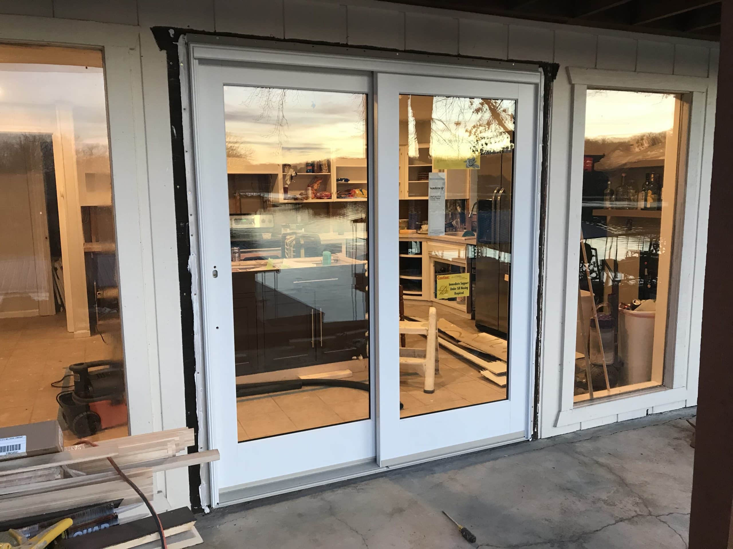exterior view from back porch area looking in throuh newly installed sliding glass door into house and kitchen 