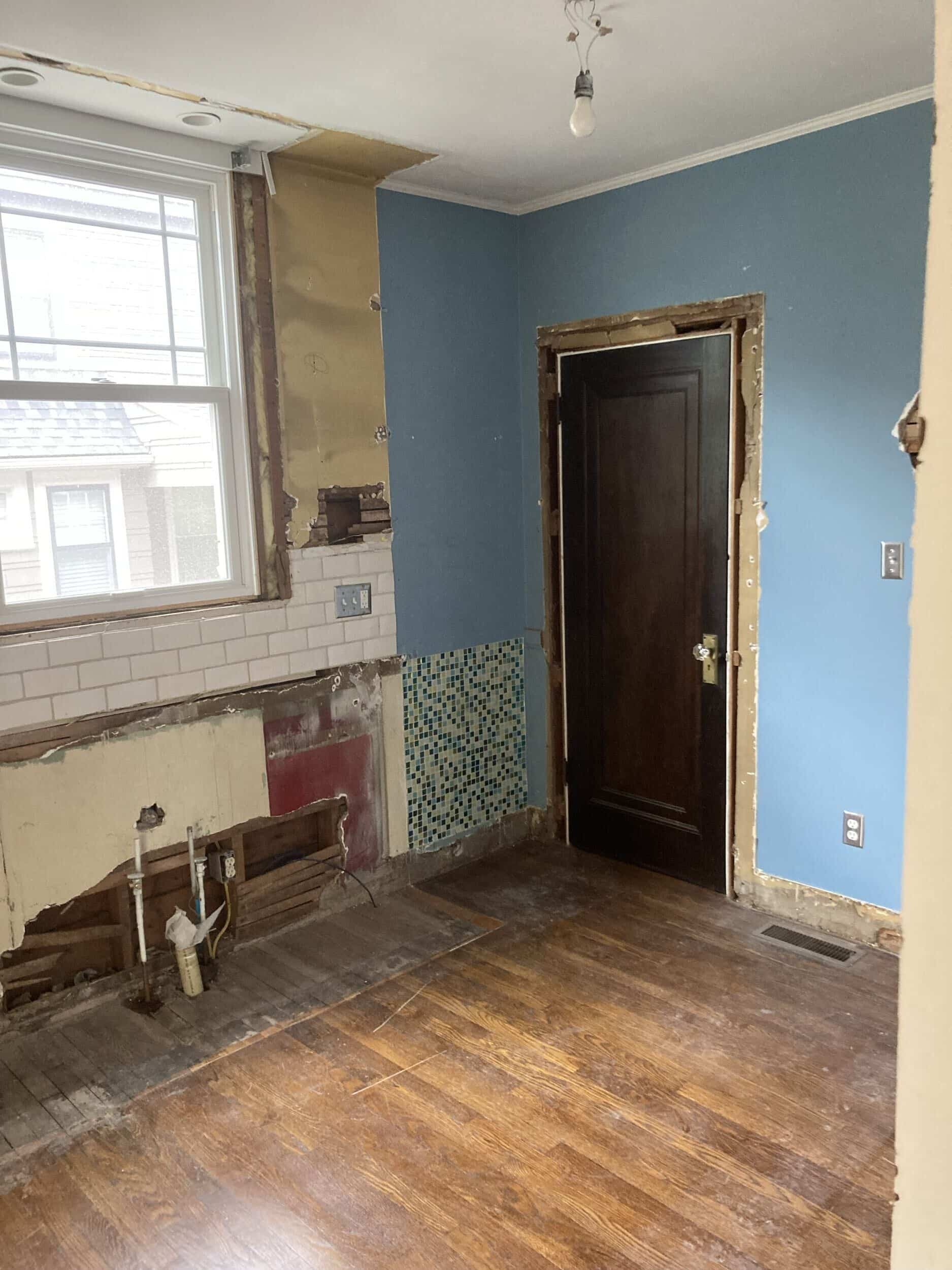other view of kitchen demo with beat up walls and cabinets and counters gone