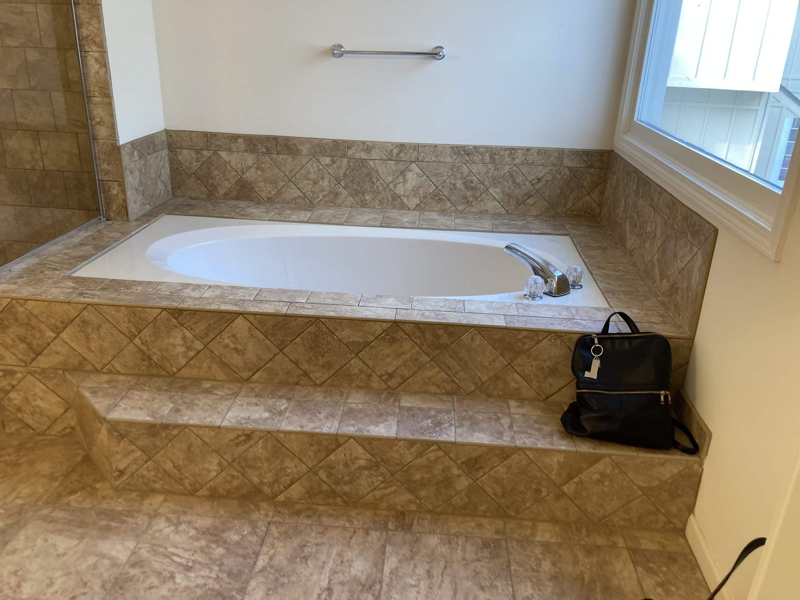 existing tub with lots of brown tile around it, looks dark and drab 