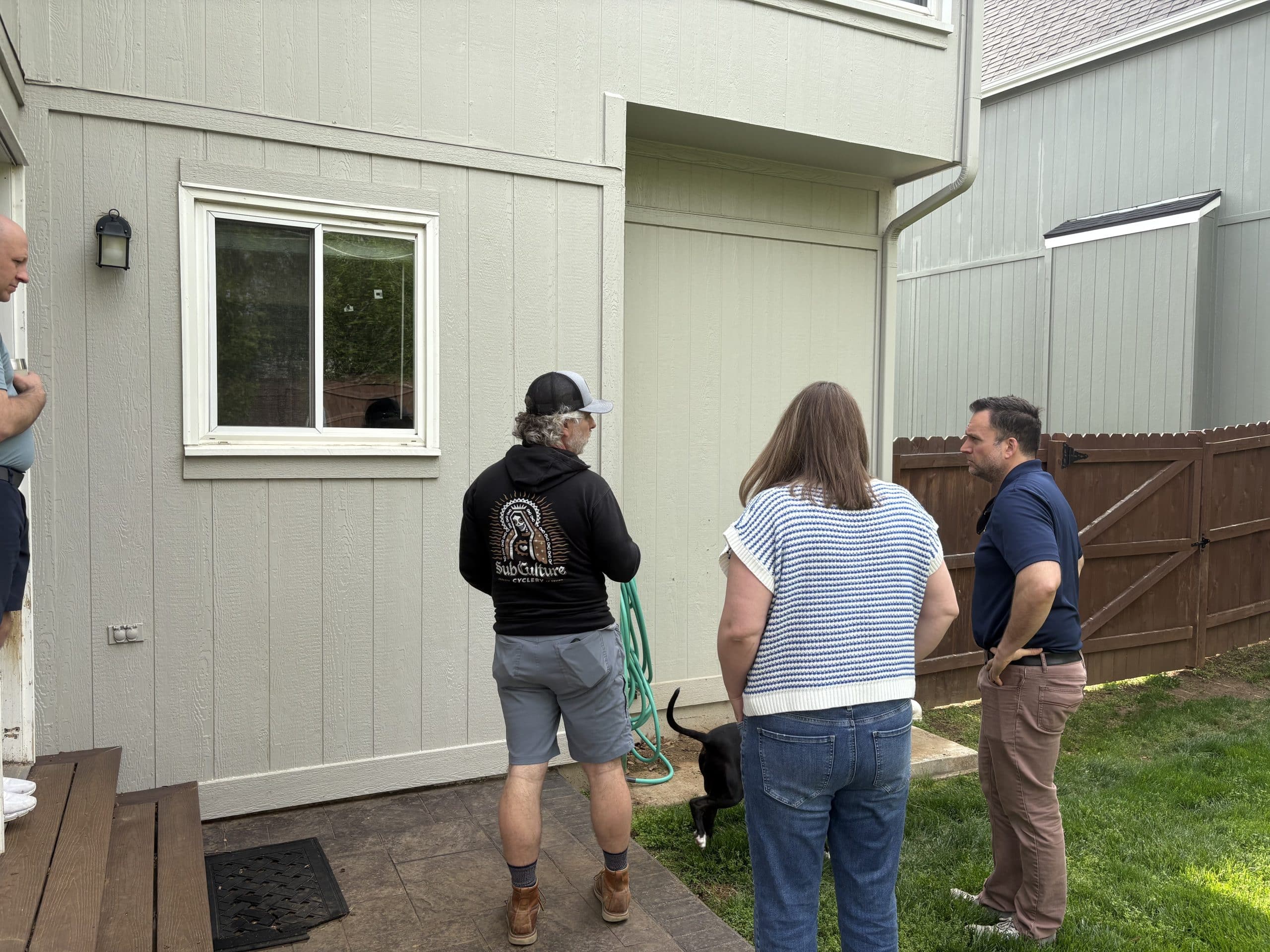 image of Jeff  Lindsay and Sean and Lindsays dog in the backyard looking up at the back of the house near the kitchen window discussing pre construction things