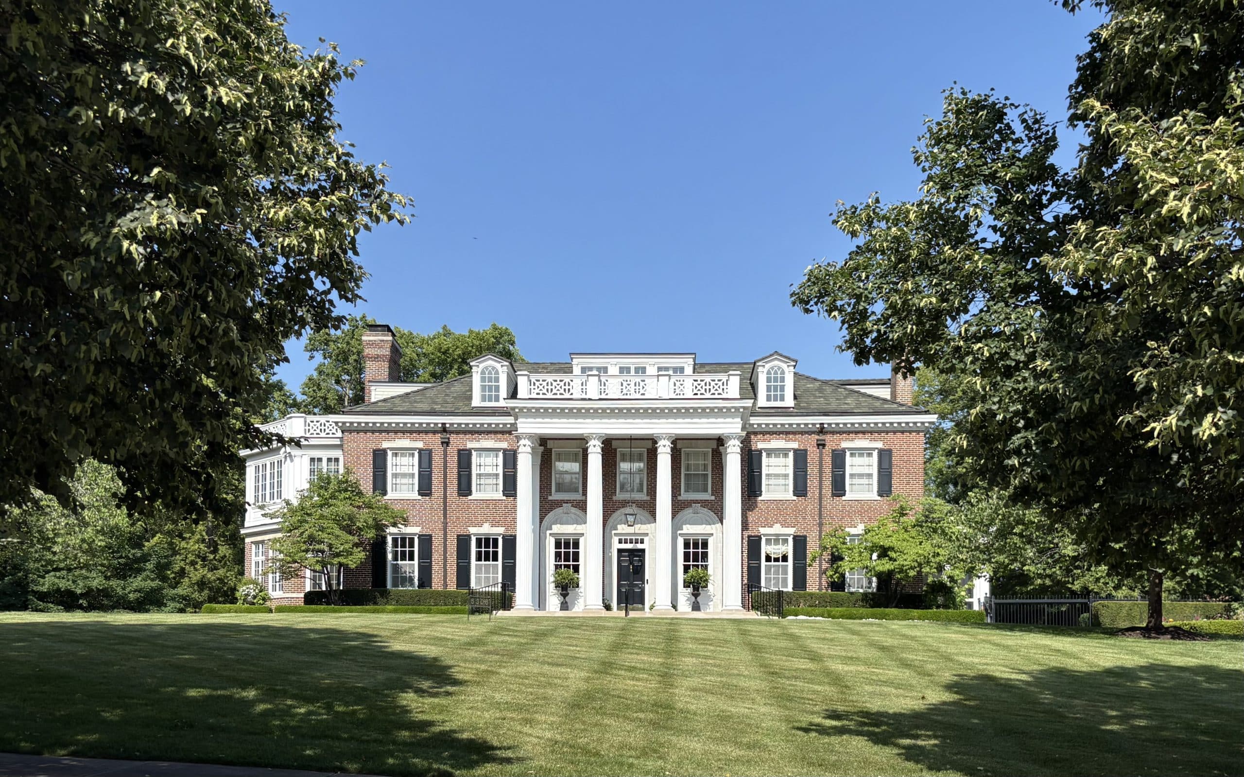 neo-classical colonial revival home in the mission hills kansas city area with white pillar columns and traditional brick with white shutters