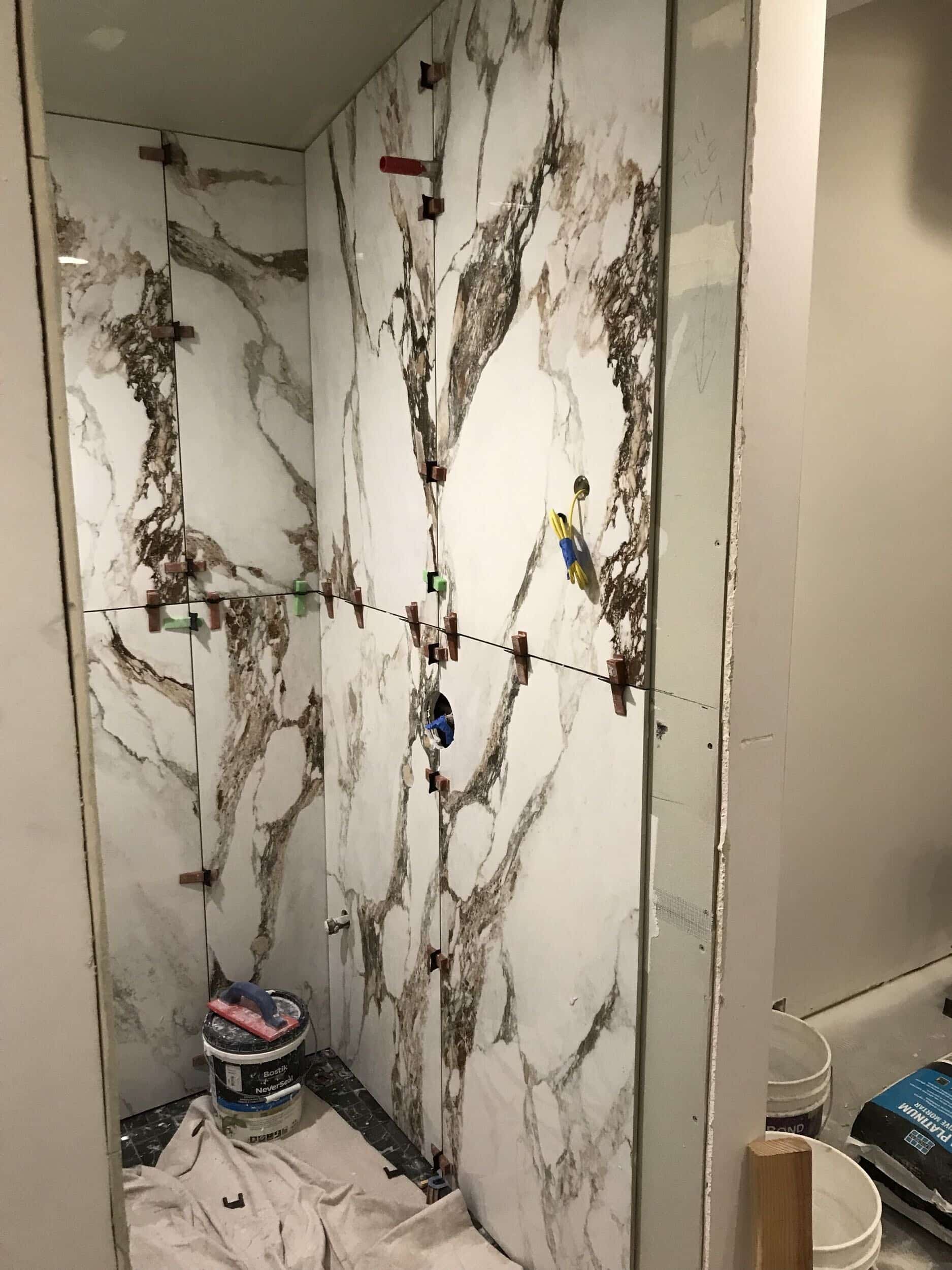 large format tile pieces now line the walls of the steam shower. the wall tile is  bright white with some charcoal and black veining