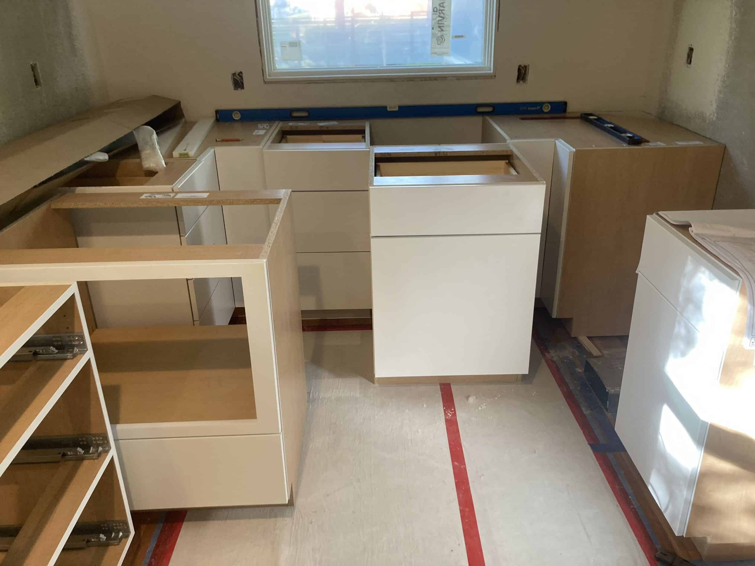 lower sleek framless white cabinets being installed in the back part of the kitchen