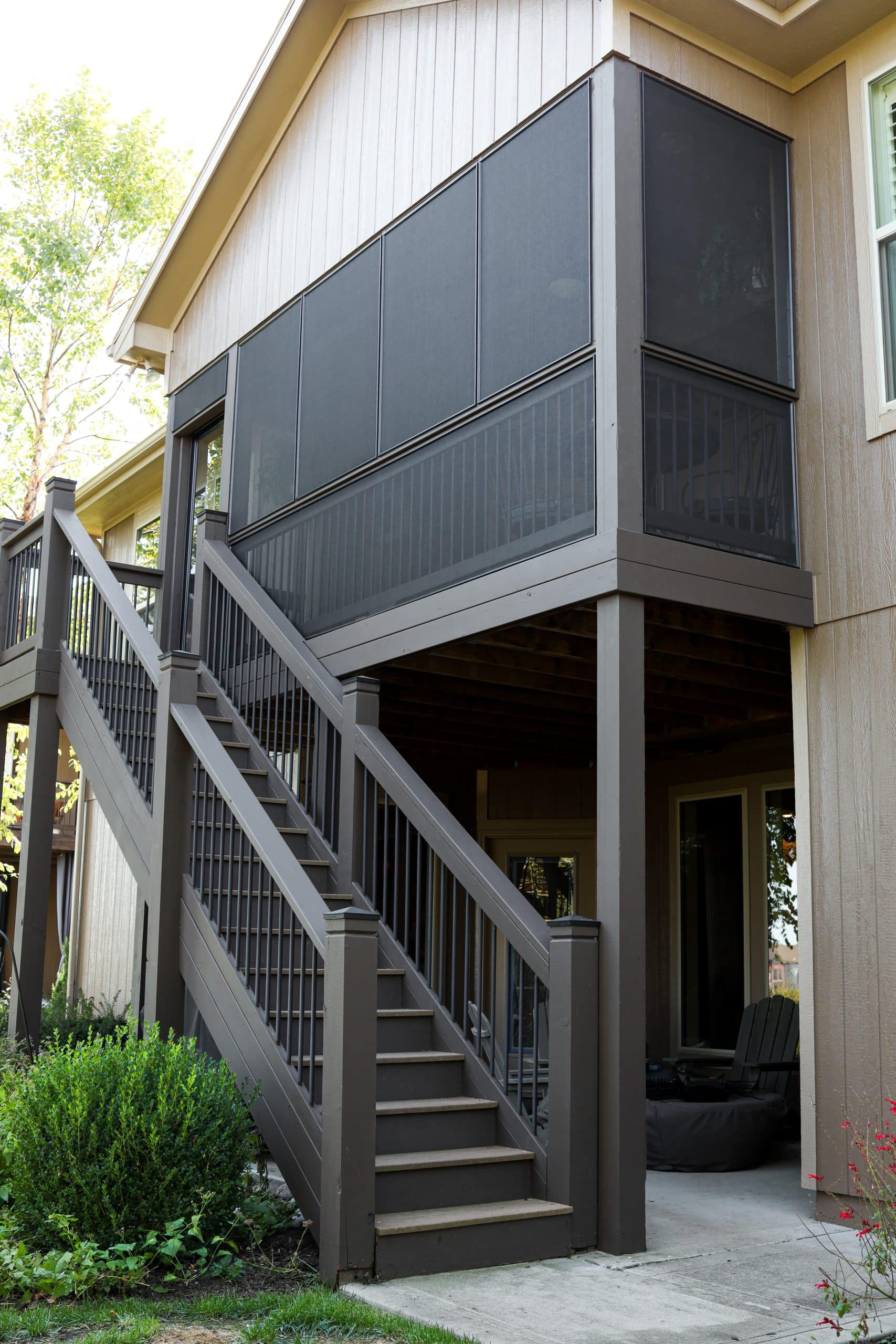 lower level exterior screened in deck photo from back yard. the screens are dark and look smooth and tight and flush with the rest of the deck and house 