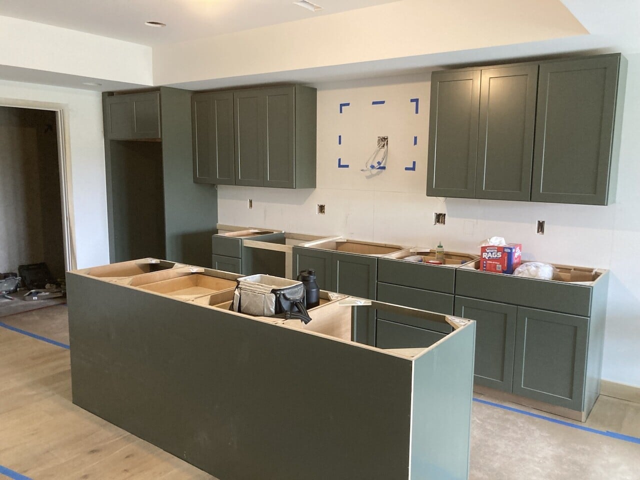 kitchen cabinets installed in basement in a netural green shade to add some personality to the upper and lower cabinets as well as the island