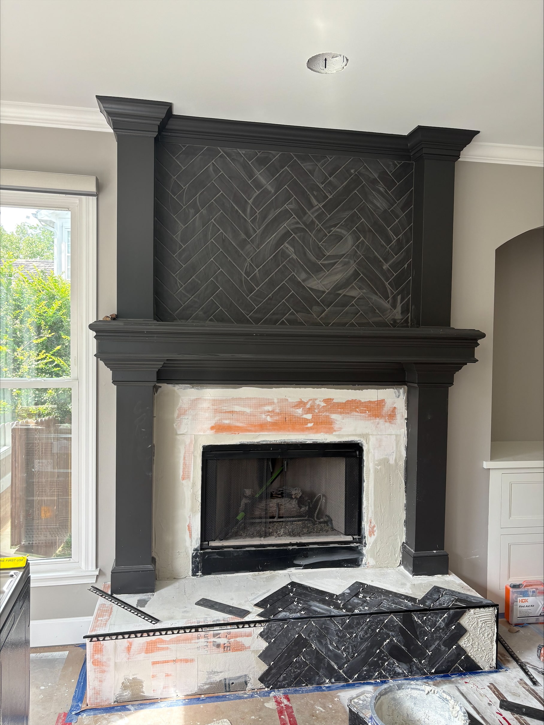 black matte black brick looking tile laid in a herringbone pattern on the fire place