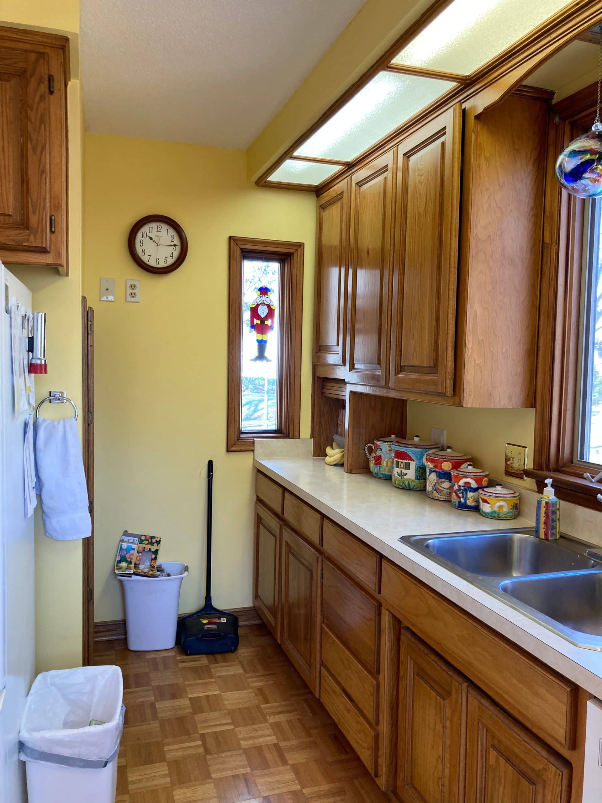 vertical view of armour hills kitchen before the remodel in kcmo showing cheap dark and dated finshes making the space feel cramped and heavy 