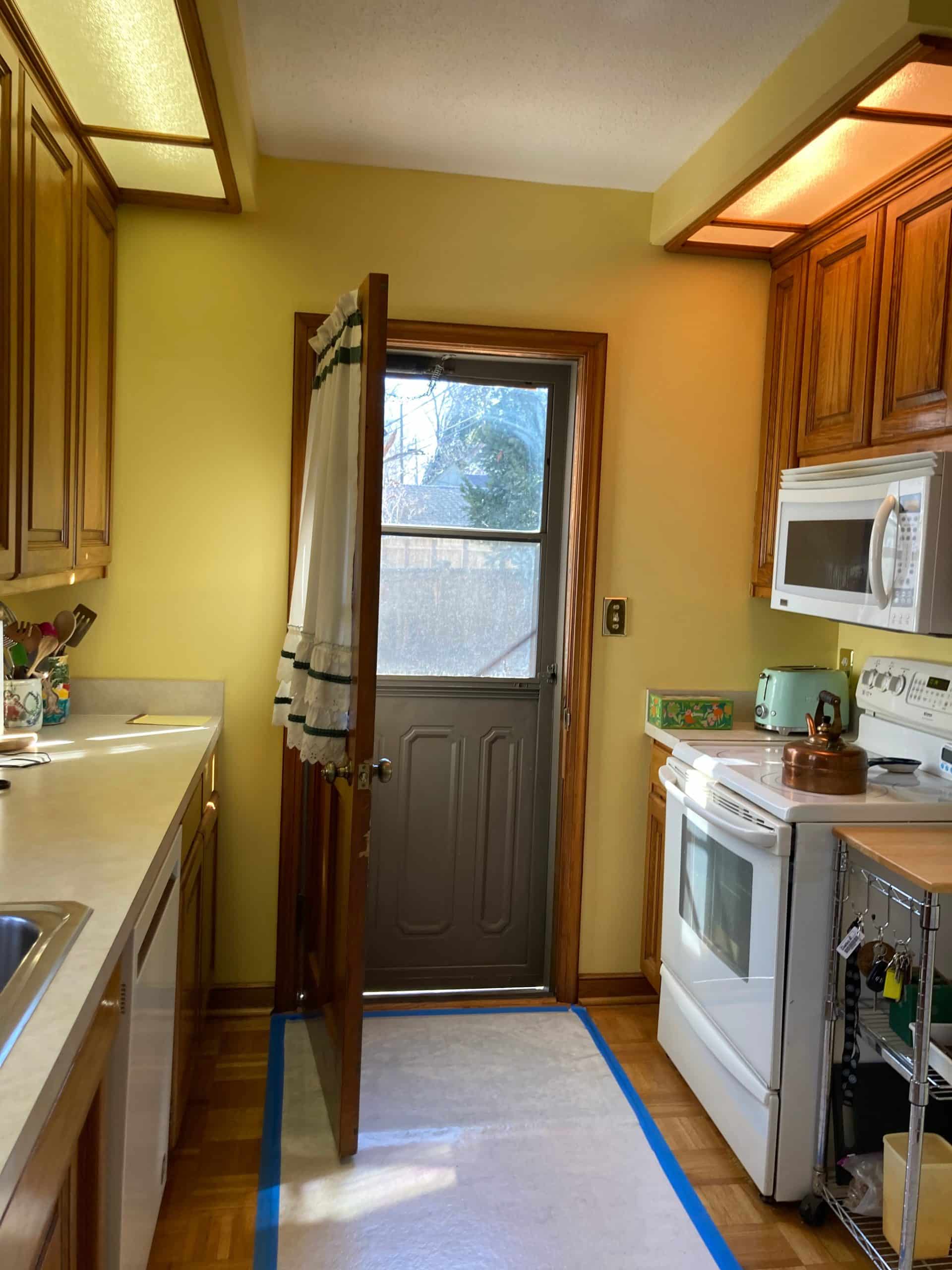 vertical view of armour hills kitchen before the remodel in kcmo showing cheap dark and dated finshes making the space feel cramped and heavy 