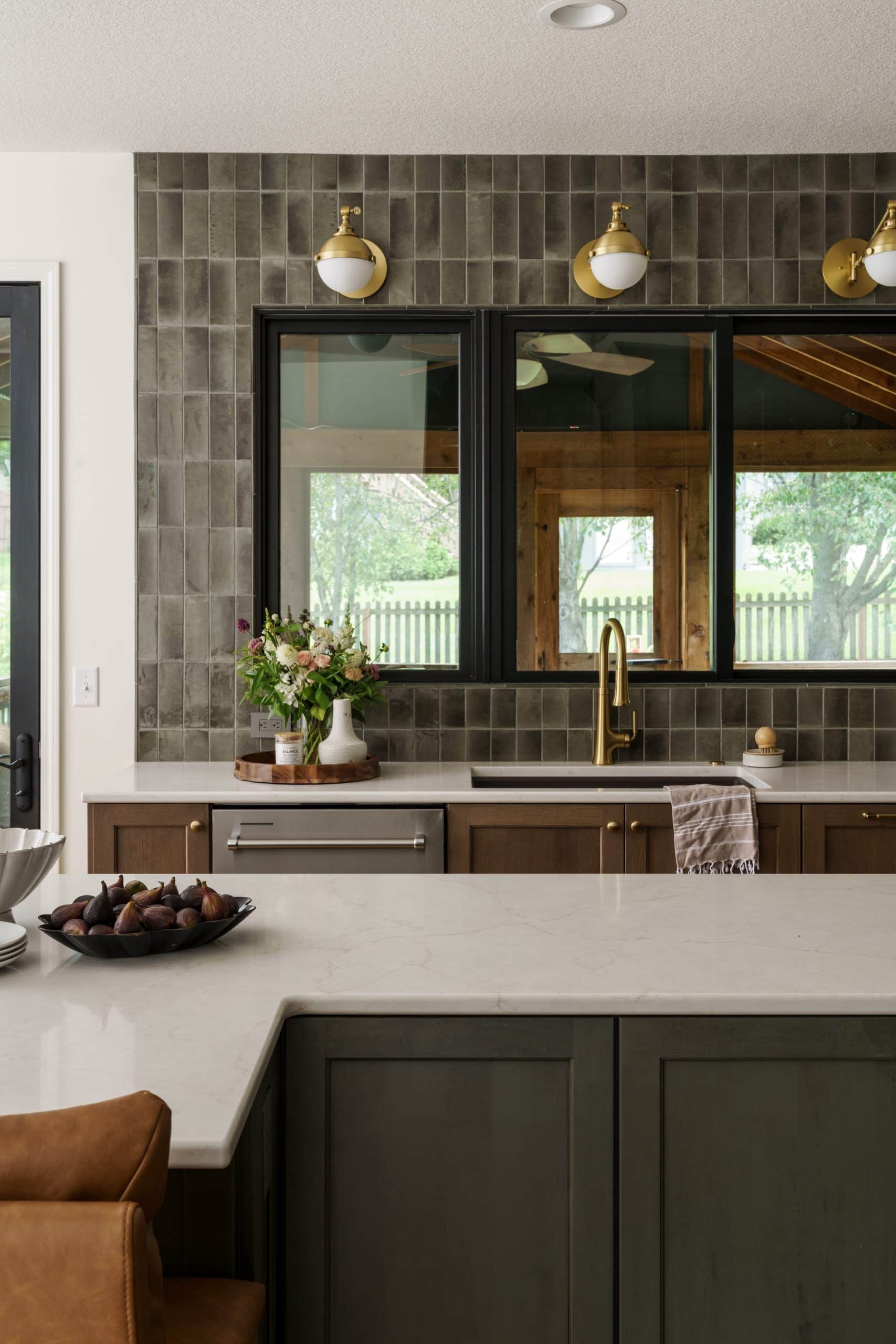 Modern kitchen design with white quartz countertops, warm wood cabinets, and a window that provides a view of the backyard, anchored by a unique high-gloss tile backsplash in Kansas City.