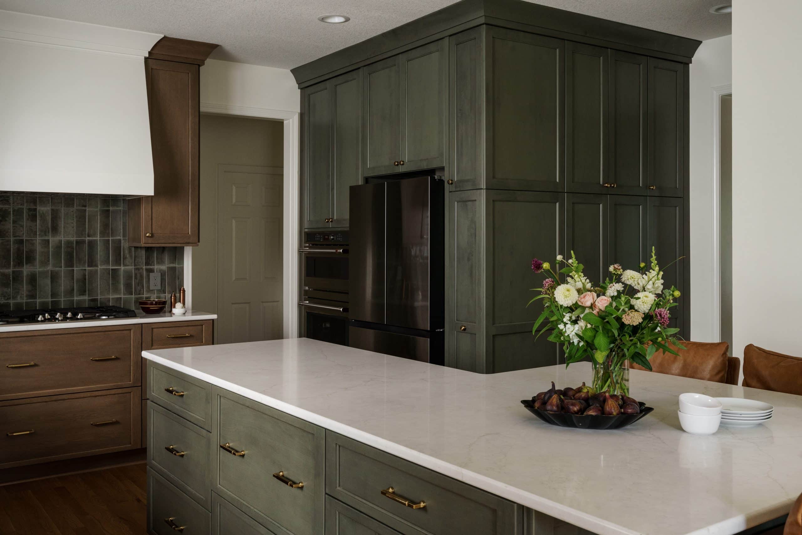 Overland Park kitchen remodel detail: Custom olive green shaker cabinetry surrounding integrated refrigerator and double ovens, maximizing storage with a modern upscale design.