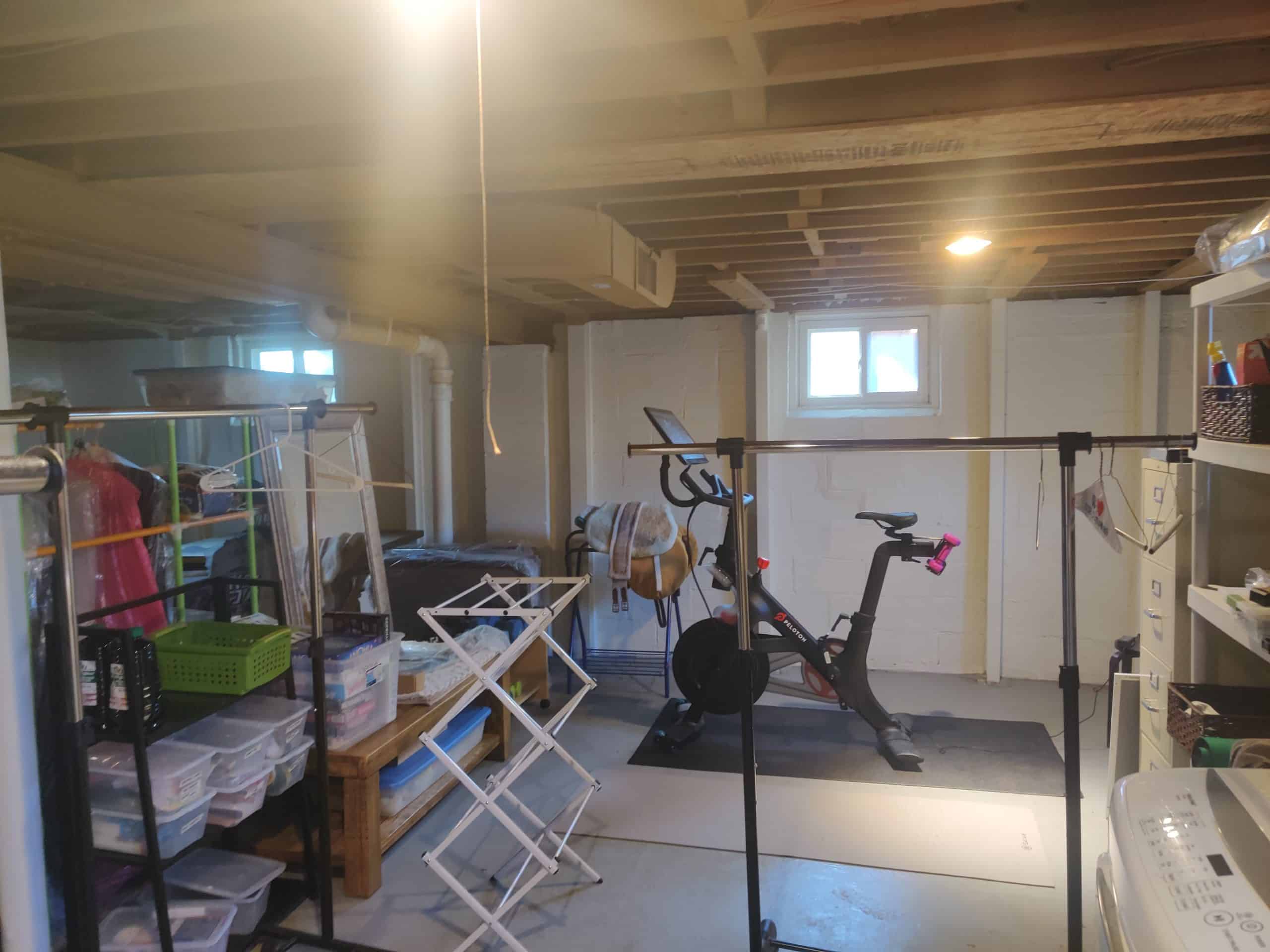 before photo of a dark unfinished basement with clutter 