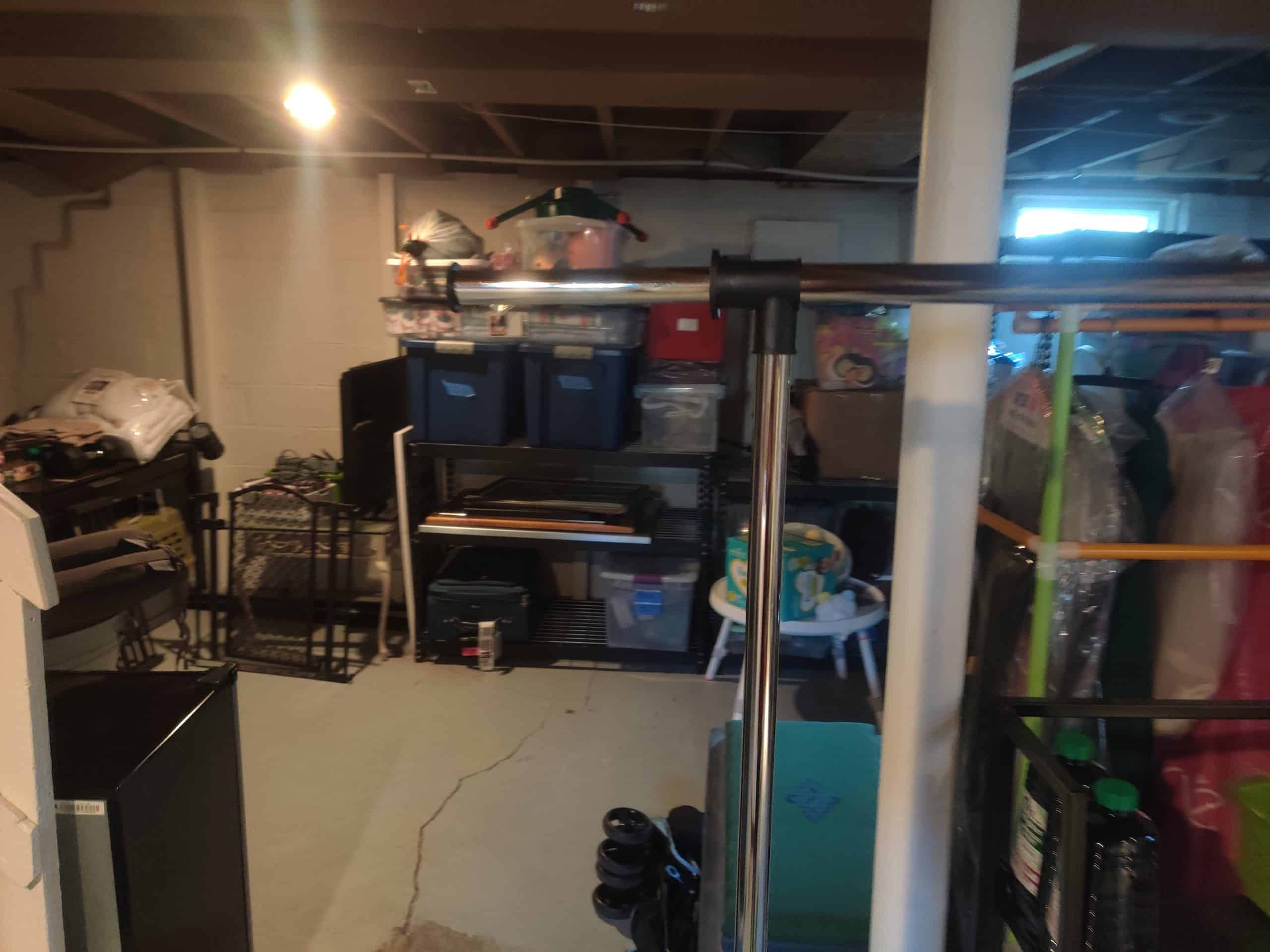 before photo of a dark unfinished basement with clutter 