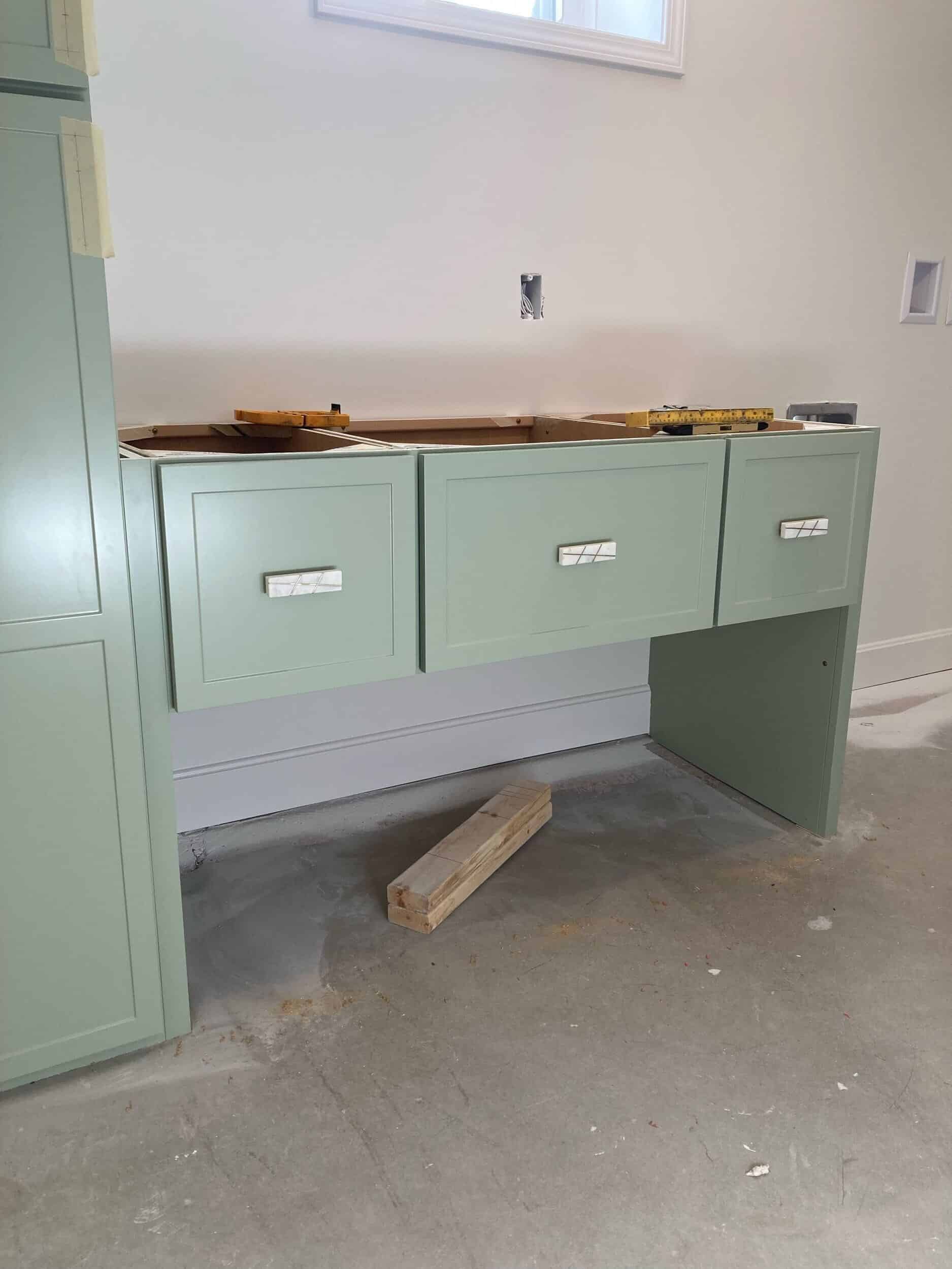 light sage green cabinetry installed in a basement remodel