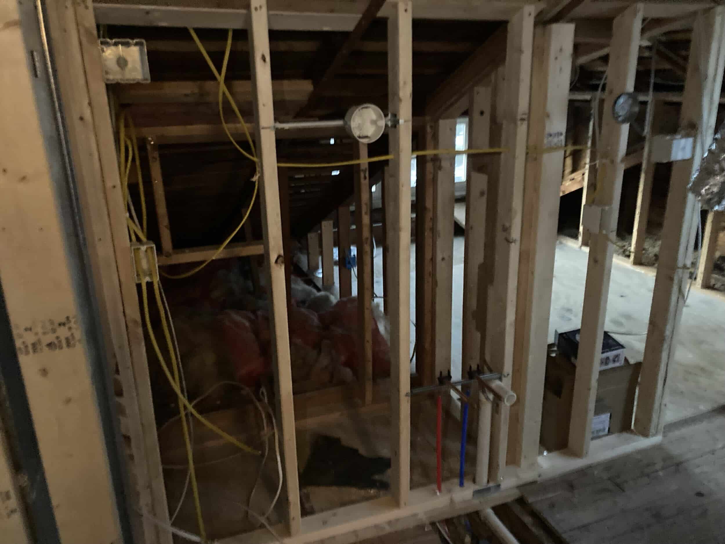 cleaning up dated tube and wire unsafe wiring in historic home remodel image shows exposed wires and plumbing lines or pies in the framing