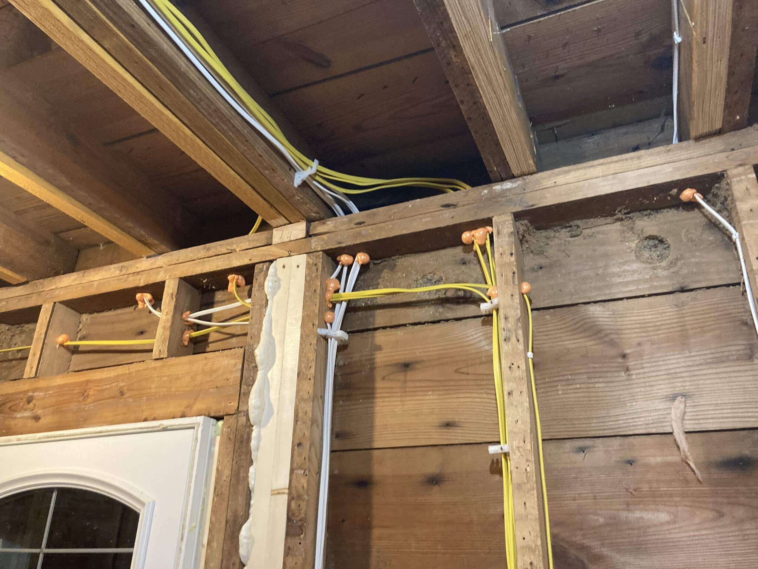 cleaning up dated tube and wire unsafe wiring in historic home remodel image shows exposed wires and plumbing lines or pies in the framing