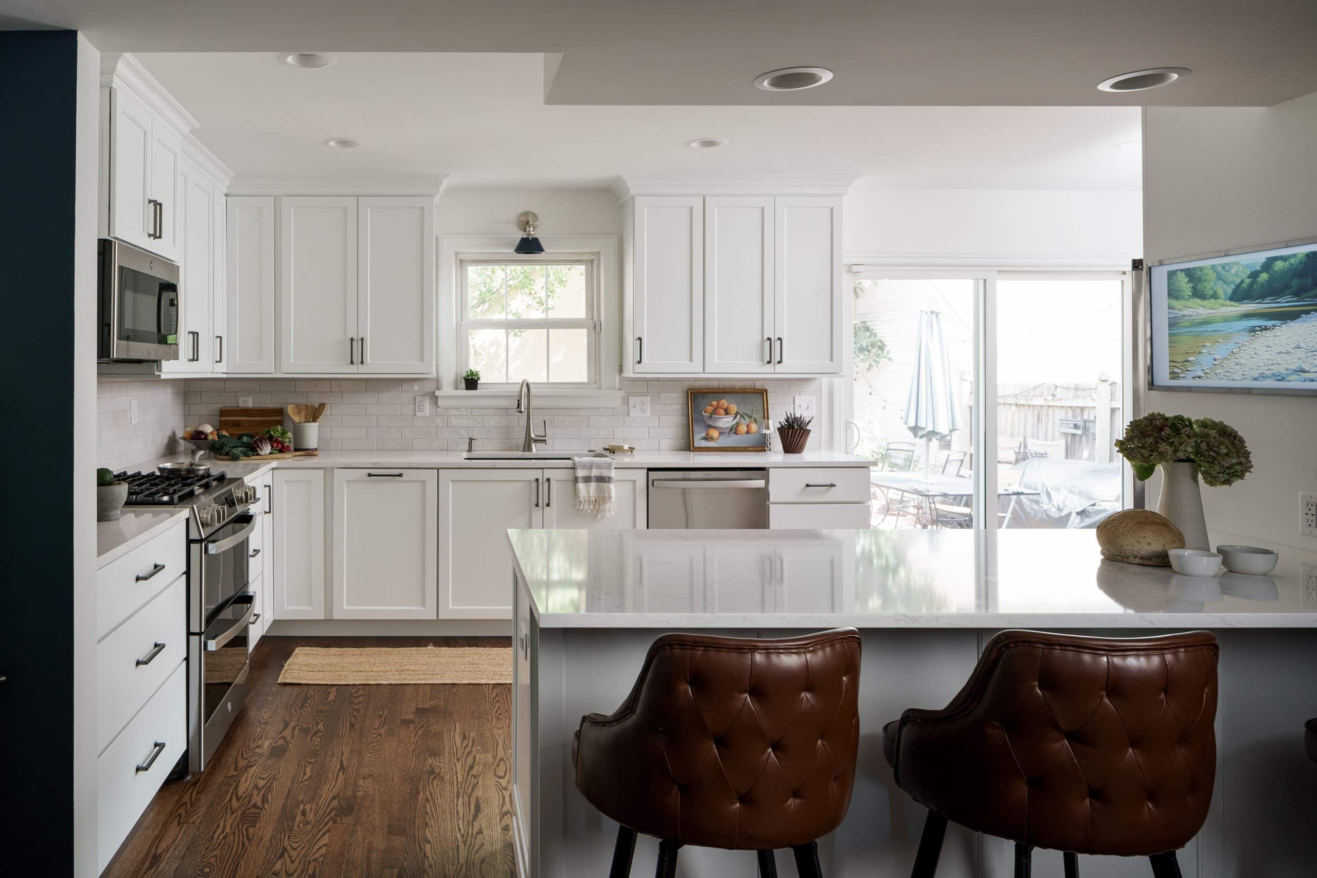 Modern Transitional Kitchen Remodel with White Shaker Cabinets and Quartz Island Modern white kitchen remodel featuring shaker cabinets, white quartz countertops, stainless steel appliances, and leather tufted barstools in a Kansas City home.