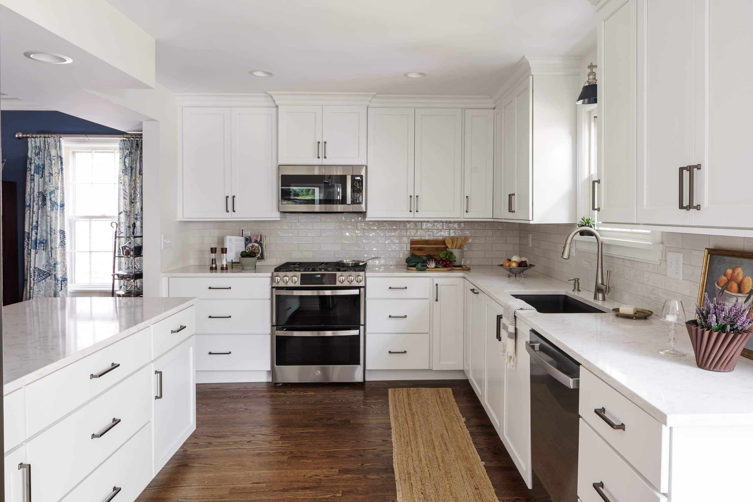 Custom L-Shaped Kitchen Renovation | Bright White Cabinetry & Quartz Countertops Bright kitchen remodel featuring white shaker cabinets with crown molding, a stainless steel double oven range, white quartz countertops, and a subway tile backsplash.