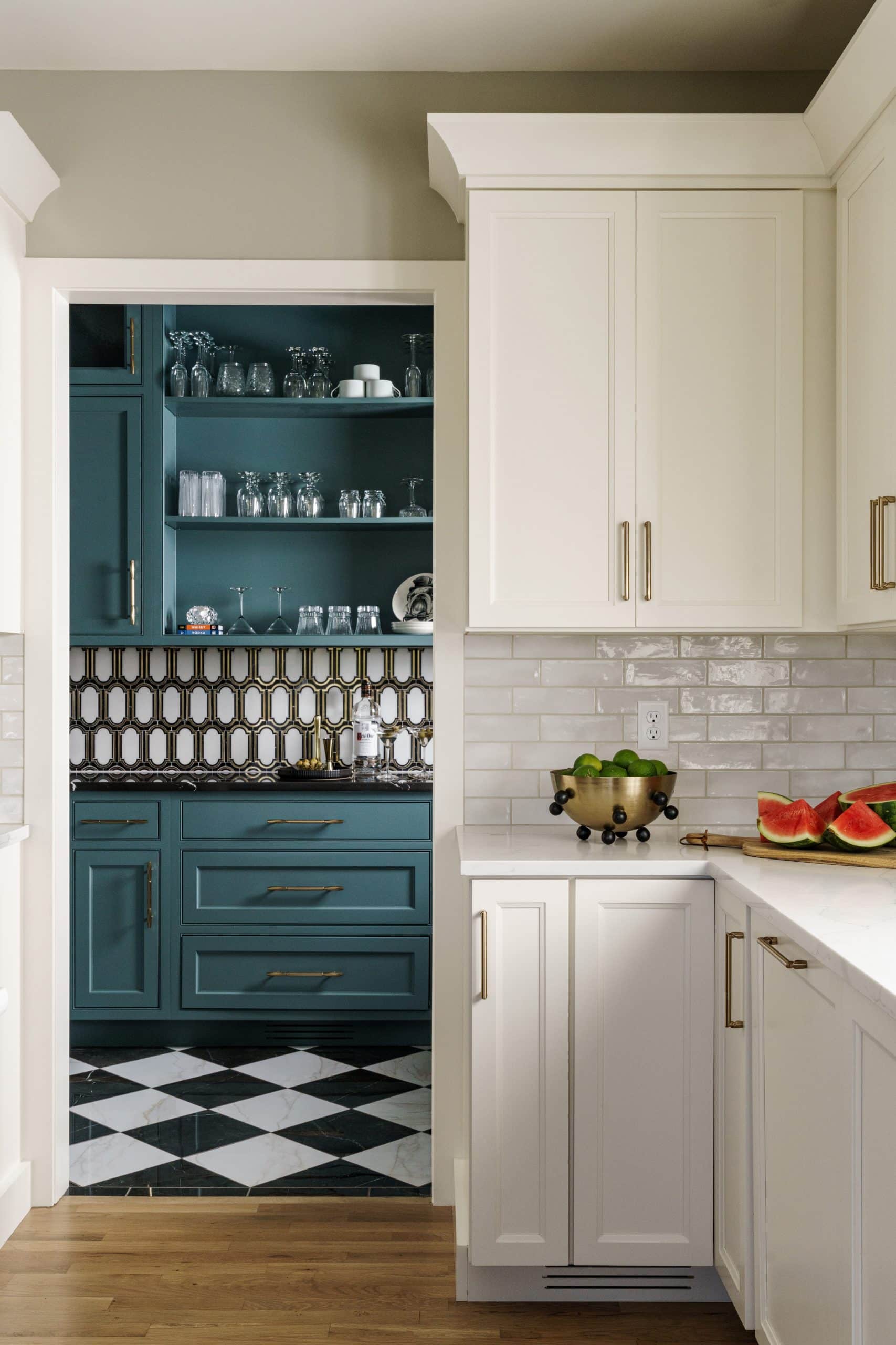 classic modern white kitchen remodel with view into moody statement art deco inspired butlers pantry with black and white checkered floor tile and teal cabinetry