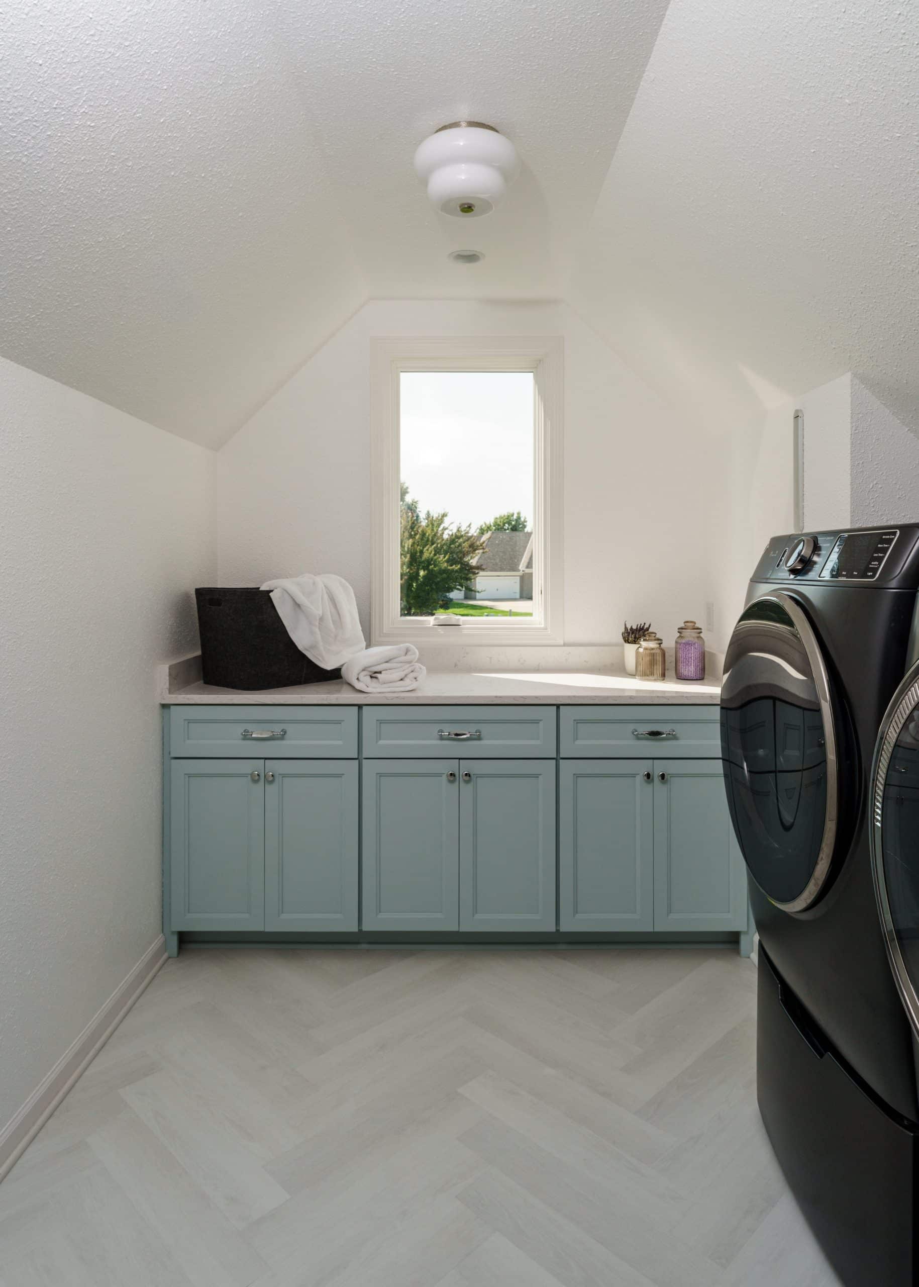 modern sleek white coastal inspired laundry room with tiffany blue cabinetry and white counters for folding laundry