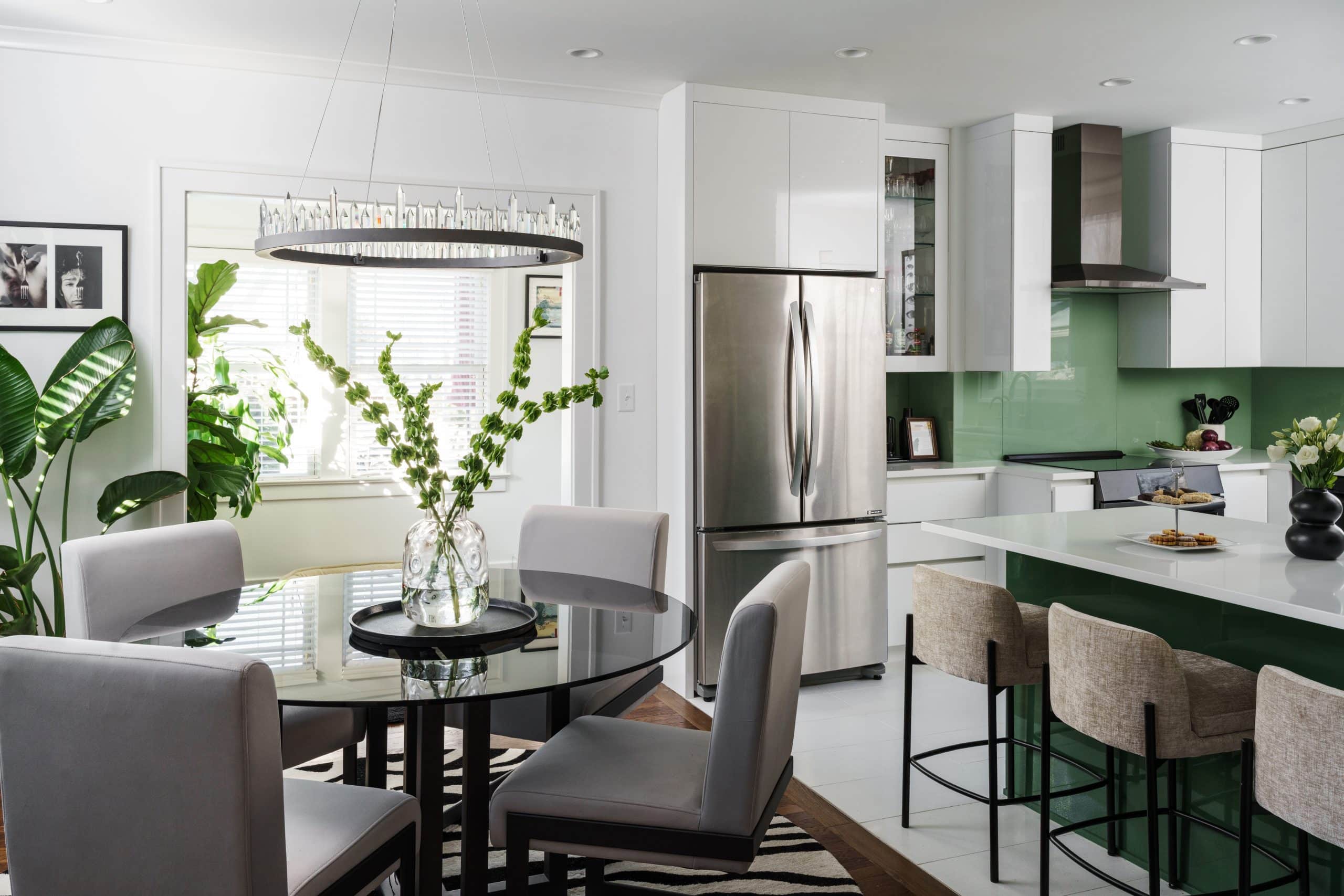 The seamless flow between a sleek modern kitchen with green gloss cabinets and an upscale dining area. Large windows and high-design lighting emphasize the European-inspired architecture of this Kansas City residential project.