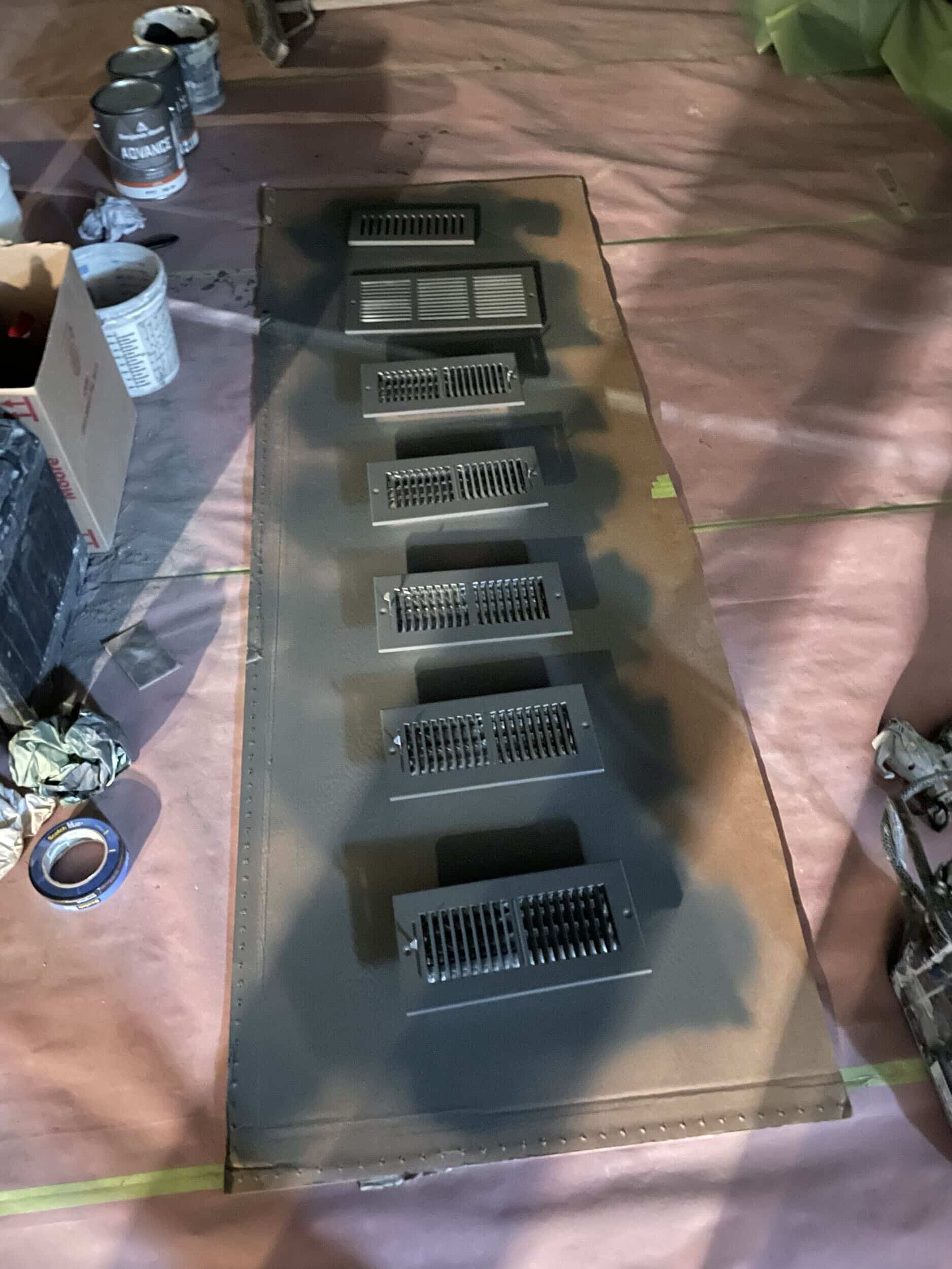 painting vent covers painting phase of basement remodel showing floor protection taped down and a light to see where the paint is being sprayed