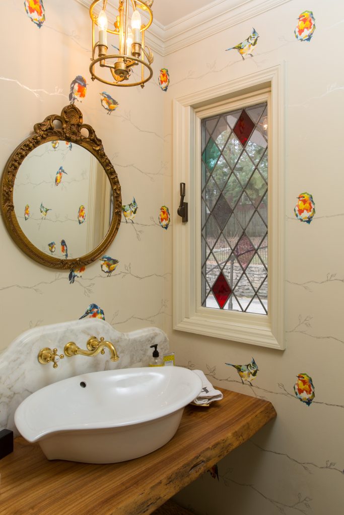 vintage charming powder bath with brass accents and wood vanity top and stain glass window