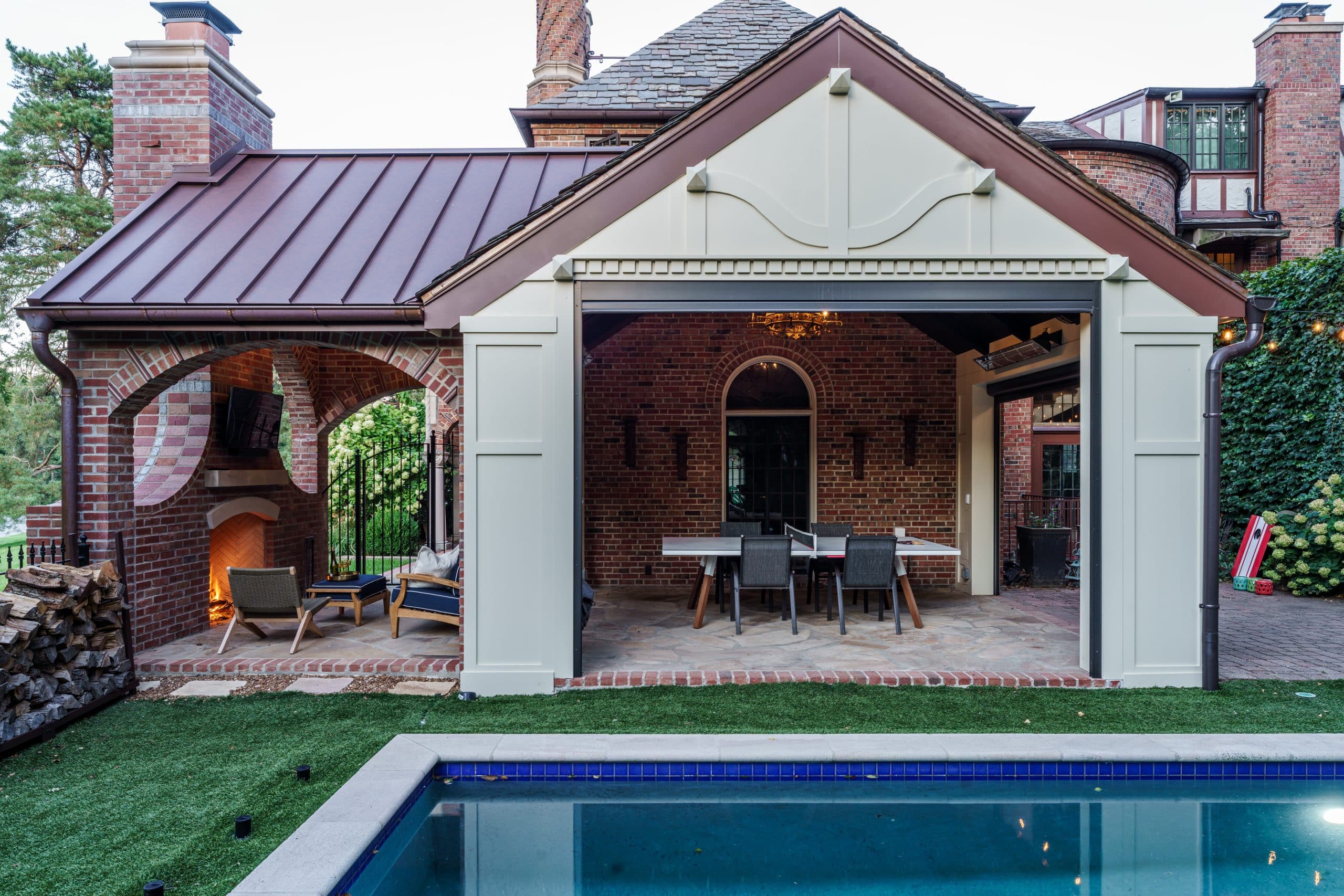 exterior view of outdoor living space remodel in Kansas City MO featuring a brick fireplace and metal roof and covered living area near pool off Ward Parkway exterior view of outdoor living space remodel in Kansas City MO featuring a brick fireplace and metal roof and covered living area near pool off Ward Parkway