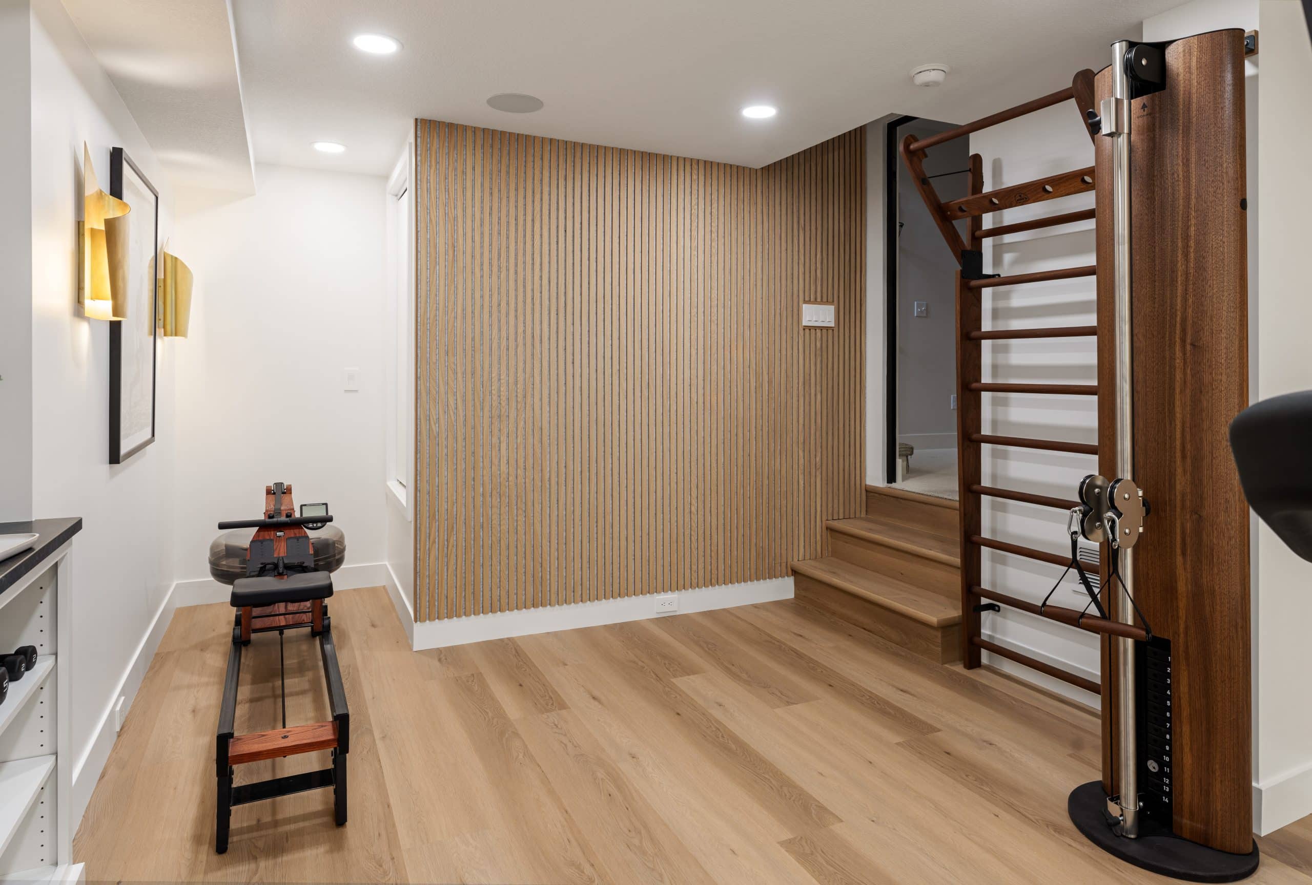 Close-up of custom slat wood wall detail in a Cedar Creek basement gym remodel, paired with black and gold accents and a luxury boutique fitness studio aesthetic.