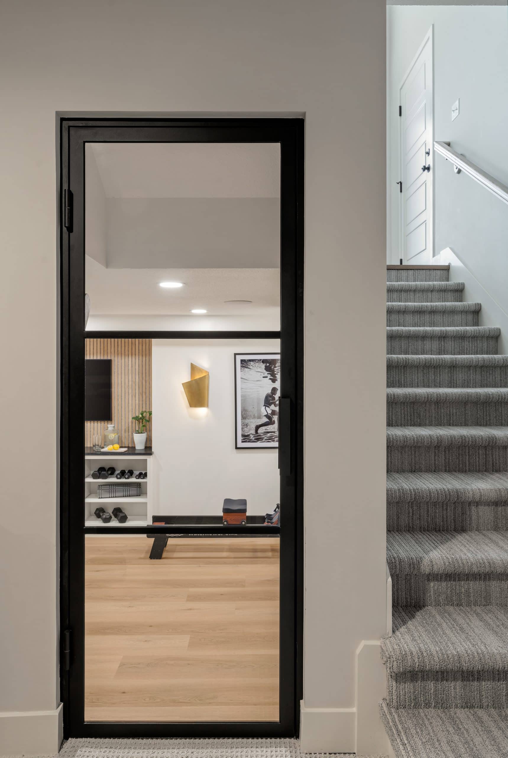 Olathe basement remodel converted into a high-end home gym with boutique fitness studio styling, light wood floors, and custom slat wall design.