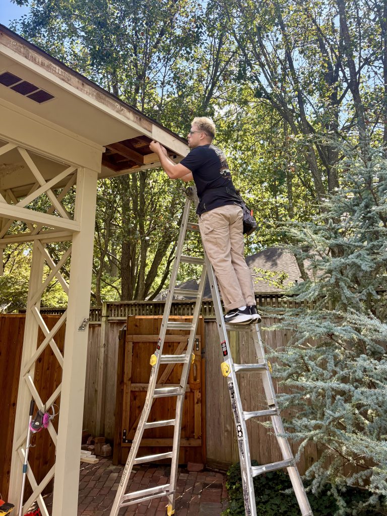 Noah Schloegel handyman on ladder removing bad parts of fascia and exterior soffit
